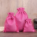 Three sizes of rose red linen drawstring gift bags displayed on a wooden surface - Rose Red