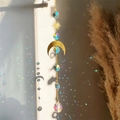 Close-up of crystal sun and moon wind chime casting rainbow reflections on white wall - Sun Moon Elements Style (03)
