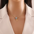 Detail of gold letter T pendant with blue evil eye charm on model wearing beige blazer - Letter T (N1339)