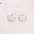 Polished silver twisted croissant hoop earrings on a white plush surface - Electroplated Silver Twisted