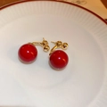 Detail of red bead earrings with golden metal link displayed on a white textured plate - 14k Gold Plated Pearl Stud Earrings