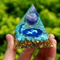 Orgone pyramid with blue gravel, gold foil and purple bead held by a hand - 6cm / A30-Blue Stone Purple Ball Zodiac