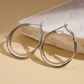 Detailed close-up of polished silver double hoop earrings displayed on a white stone base - 30MM / Silver