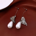 Close-up of 18k gold plated drop pearl earrings on luxurious dark silk fabric background - Silver