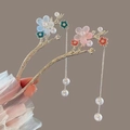 Detail of Chinese tassel hairpins with magnolia flowers and pearls held in lace hand - Blue Peach Blossom