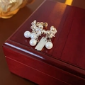 Dettaglio macro di un elegante ear cuff con zircone, perle bianche e catena in metallo argento - Argento