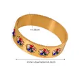 Vista macro di un bracciale largo in oro 18k con fiori di zirconi colorati e bordi incisi - Bracciale Floreale Dorato con Strass Colorati