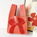 Knitted wrist tote bag in coral orange with red bow pattern and integrated handle - 20*35cm / Coral Pink & Red Bow