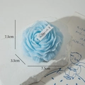 Sky blue peony shaped scented candle with layered petals and small paper tag - Blue