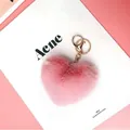 Dettaglio di un portachiavi a cuore in peluche rosa con chiusura in metallo dorato - Rosa