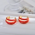 Macro view of triple-layered red and gold hoop earrings with polished enamel finish - Red