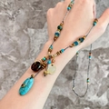 Detail of bohemian long beaded necklace with shell pendant and gold brand tag - Oval Pendant Style / Blue