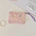 Nahaufnahme der rosa gewebten Kosmetiktasche mit Reißverschluss und lila Kordel auf dem Tisch - Rosa