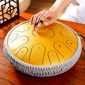 Yellow steel tongue drum with woven rope decoration placed on a wooden table - 13 Inch 15 Notes - Gilded Gold - Maple Leaf