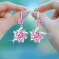 Pink heart-shaped zircon windmill earrings in silver setting, shown held by hand - Rotating Snowflake Earrings [pink Diamond] Led-76