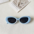 Detail shot of baby blue chunky oval sunglasses with dark lenses on a textured surface - Blue Gold