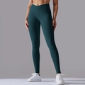 Detailed view of the crossover V-waist design on dark green seamless yoga leggings - Teal