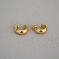 Gros plan de boucles d'oreilles créoles en C en laiton plaqué or sur tissu texturé - Doré