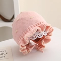 Gros plan du bonnet tricoté rose pour bébé avec bordure à volants et dentelle - 6 mois - 2 ans / Rose