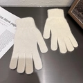 Nahaufnahme cremefarbener Strickhandschuhe mit weicher Textur und gerippten Bündchen auf Holz - Einheitsgröße / Gebrochenes Weiß