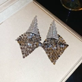 Gros plan de boucles d'oreilles à pompons argentées avec strass dans un coffret à bijoux - Losange en Maille Métallique Entièrement Serti de Diamants Argenté (Tige en Argent)