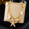 Goldenes Bettelarmband mit Meeresanhängern wie Seestern und Schildkröte auf Display - Schildkröte Seestern Muschel Delfin Armband Stil (N3545)