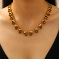 Detailopname van een vintage gouden gotische schedelketting met hangers gedragen door model - Antiek Goud (1633)