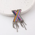 Rainbow rhinestone X-letter brooch with shimmering crystal tassels on a stone tray - Letter X
