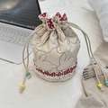 Macro detail of beige quilted drawstring pouch with red rabbit embroidery and plaid trim - Quilted Rabbit Cream White