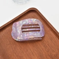 Macro detail of lavender iridescent acetate hair claw clip on a dark wood tray - Pearlescent Claw / Purple Mermaid
