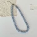 Macro detail of aquamarine natural stone beaded necklace with silver clasp on white background - 10mm / Blue