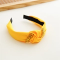 Detail of yellow fabric headband featuring a knotted design and sparkling gold rhinestones - Yellow