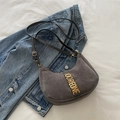 Chic grey suede crescent underarm bag with gold metal letters on denim background - Gray