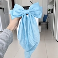 Elegant large blue satin bow hair clip with long ribbons in a handheld display - Blue