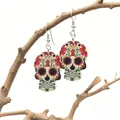 Macro detail of acrylic Day of the Dead skull earrings hanging on a rustic branch - Cream White with Red Yellow Black Pattern