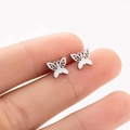Minimalist hollow butterfly stud earrings in silver-tone metal shown held by hand - Steel