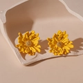 Detailed macro shot of yellow flower studs with golden center on minimalist tray - Yellow
