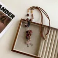 Detail of bohemian necklace with Believe metal plate and fabric flowers on tray - 9# Necklace-Coffee