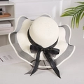 Detail of wide brim straw hat with wavy mesh trim and golden lettered black ribbon bow - Mesh Edge Creamy White