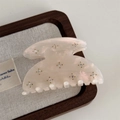 Macro shot of starry rhinestone embellishments on a cream acetate hair claw clip - Pink White
