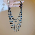Detail einer mehrlagigen Quastenkette mit blauen Kristallen und Herzanhänger mit Perlen - Blaues Herz Mehrlagiger Stil