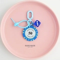 Macro shot of blue poker chip keychain with lucky dice on a pink ceramic plate - Blue-50 Value