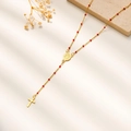Detalle del collar rosario chapado en oro de 18K con cuentas rojas y colgante cruz - Rojo