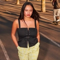 Top corsé negro con cordones y pantalones a cuadros amarillos en un entorno urbano al atardecer - S / Negro