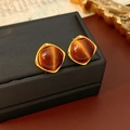 Macro-detail van vintage barnsteen katteoog-oorbellen met gouden vierkant frame - Zilveren Pin Vierkante Ronde Stijl / Bruin