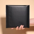 Self-adhesive black bubble mailer for secure shipping, held by hand for scale reference - 35x45+5cm / Black