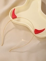 Dettaglio macro di corna di diavolo rosse lucide su cerchietto in metallo dorato sottile - Cerchietto con corna rosse lucide