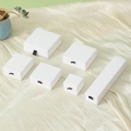 Various sizes of white drawer-style jewelry boxes with black ribbon pulls on silk fabric - Matte White