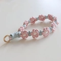 Detail of hand-woven daisy flower keychain with pink and blue cord and gold metal ring - Korean Pink