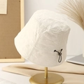 Beige quilted bucket hat with adjustable drawcord on a gold display stand - M (56-58cm) / White